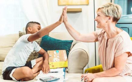 An adult woman and a school-aged boy exchange a high-five in an office environment.