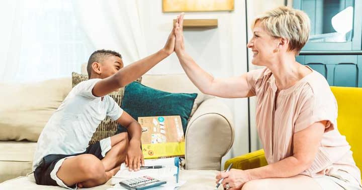 An adult woman and a school-aged boy exchange a high-five in an office environment.